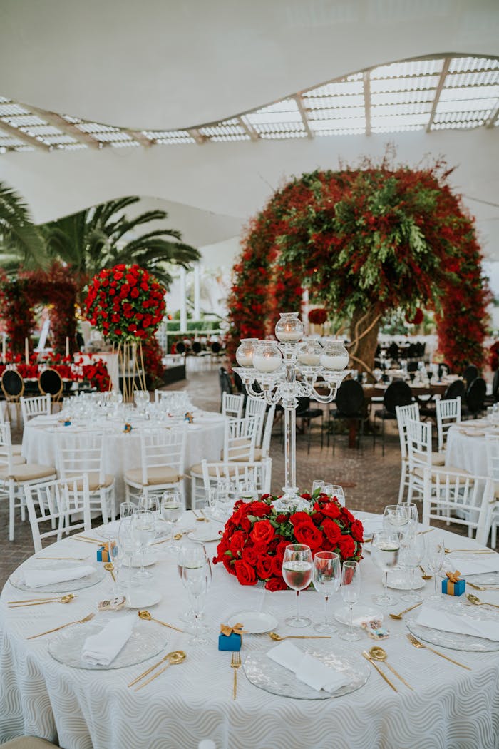 Elegant outdoor wedding reception with red roses and white tables, creating a luxurious ambiance.