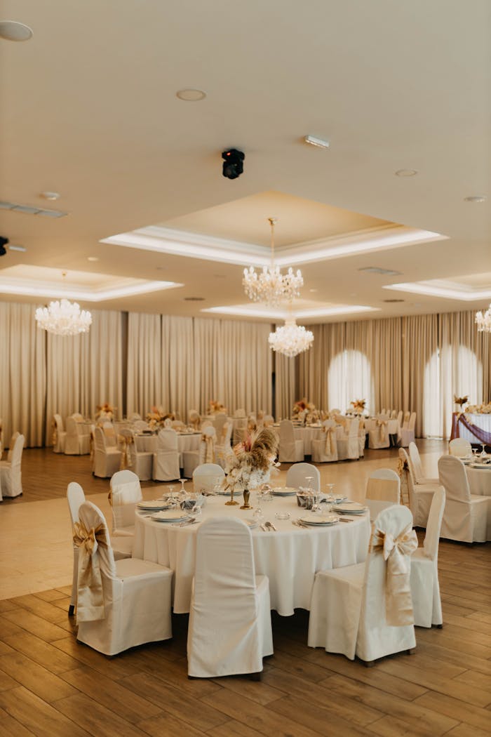 Luxurious wedding banquet hall with chandeliers and round tables elegantly set.
