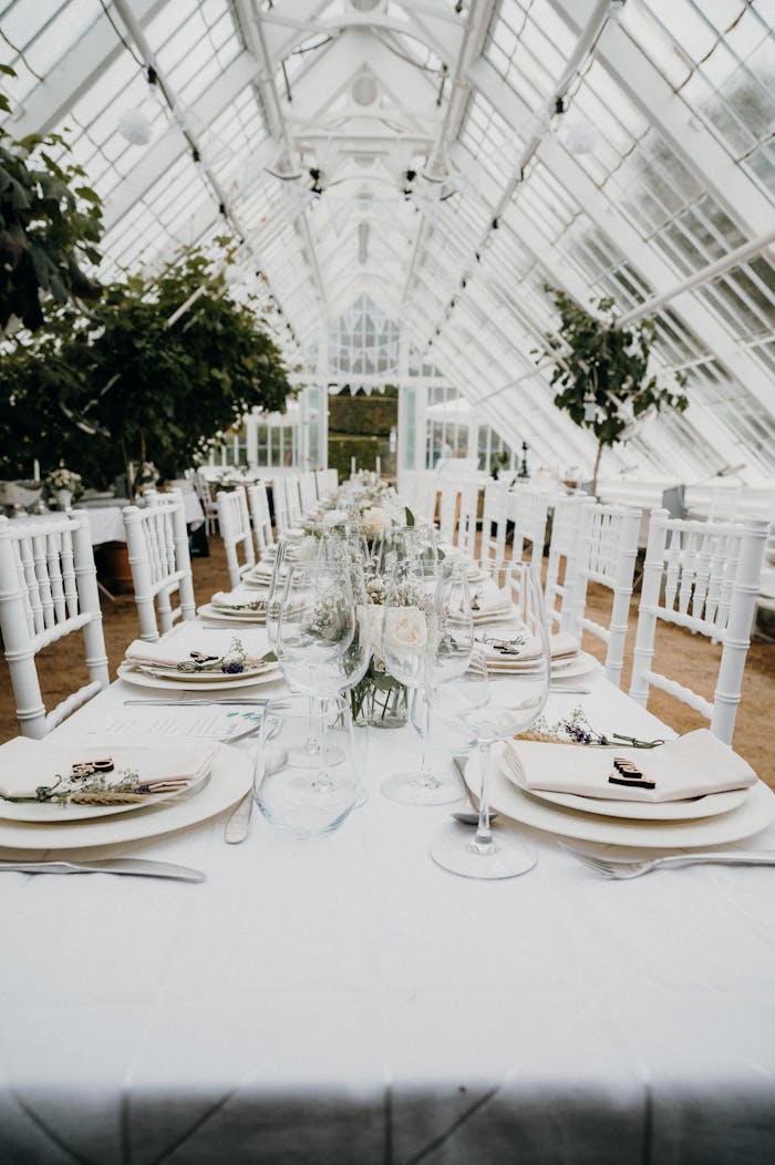 Beautifully decorated wedding table inside a lush greenhouse setting, perfect for a romantic celebration.